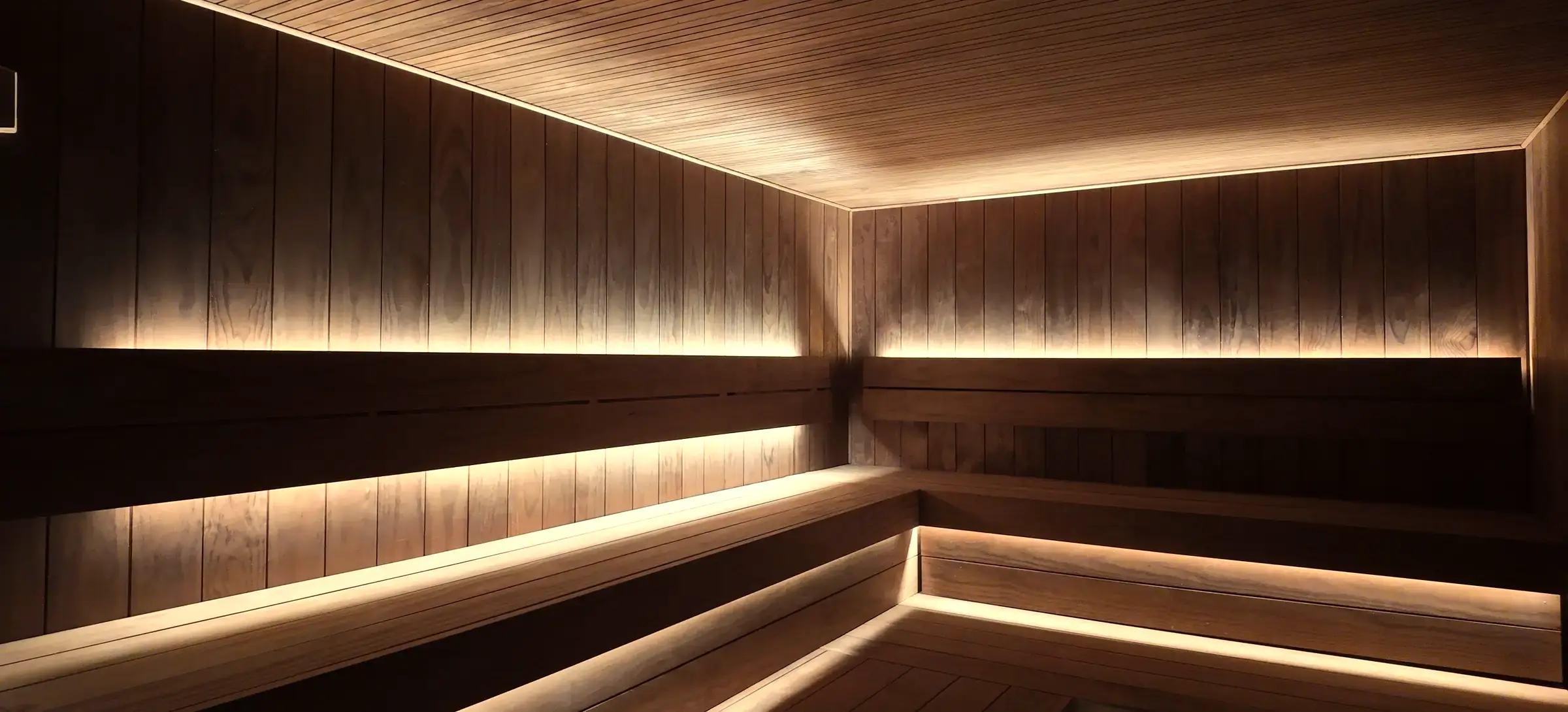 The empty sauna at Pulse Club Fulham, lit low along the benches