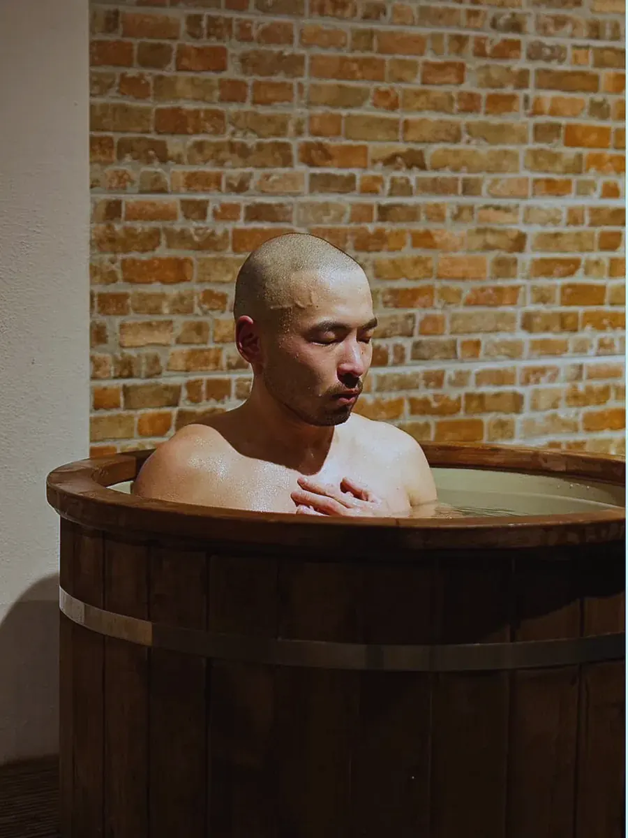A member breathing slowly with a hand on his chest in the cold plunge