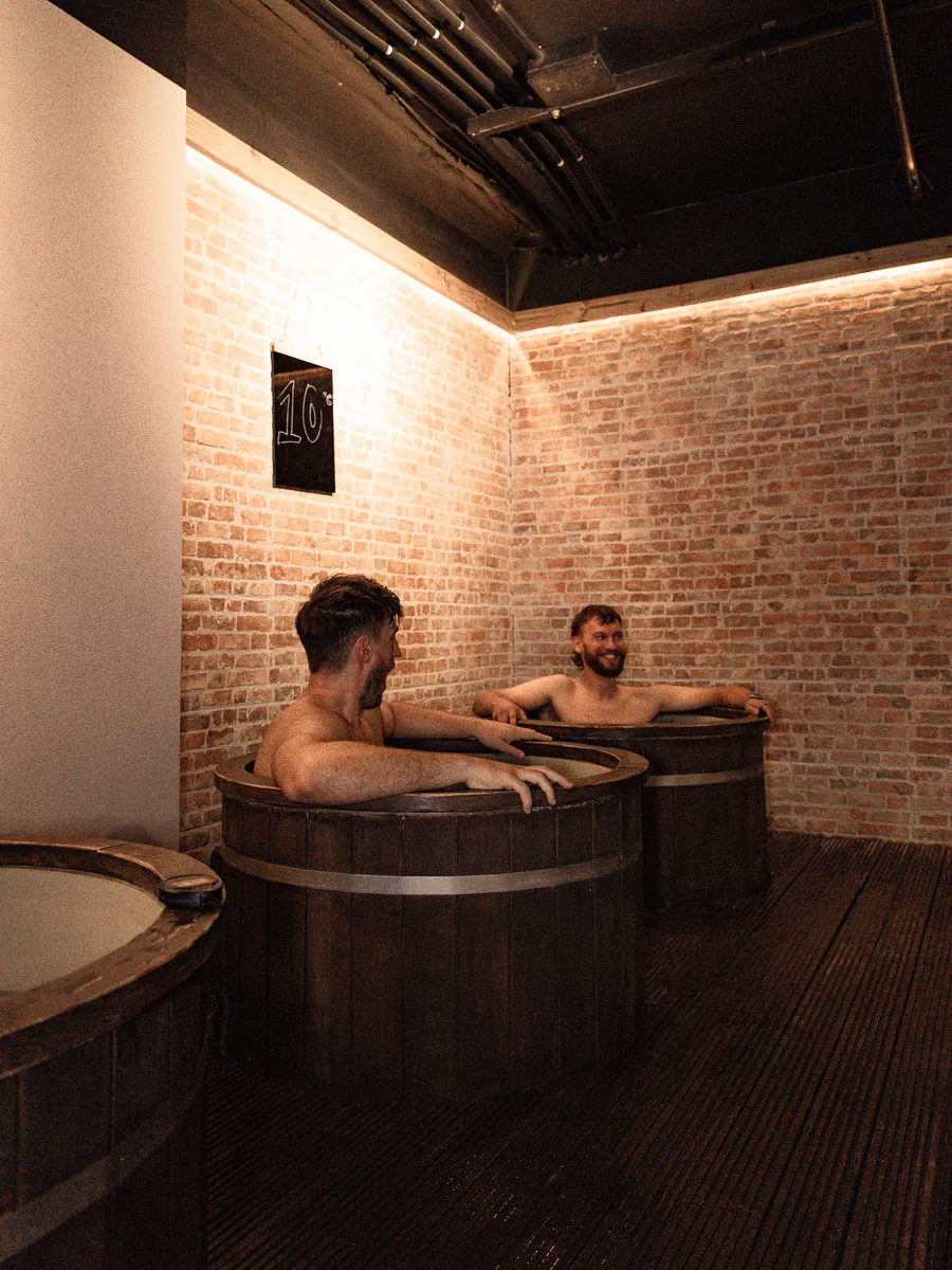 Two members chatting across the cold plunges at Pulse Club Fulham
